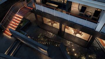 A multi-level building with a staircase, outdoor seating area, and a pool.