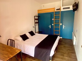 Un dormitorio con cama, escritorio, armario y una escalera.