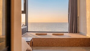 Una habitación con un ventanal grande con vistas al mar, un banco de madera y un radiador.