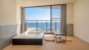 A balcony with a hot tub, a table, and a view of the ocean. - Sokcho W&jiseda Spa Poolvilla (Sokcho)