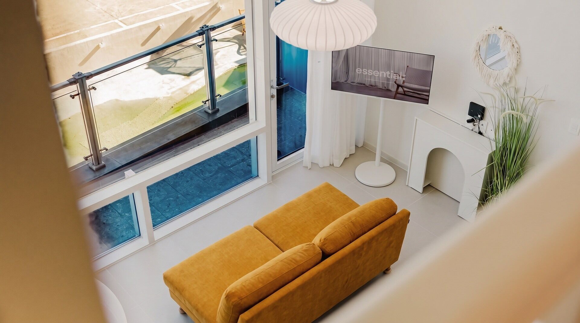 A modern living room with a sofa, a television, and a decorative mirror.