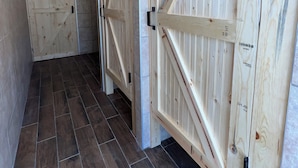 Un pasillo con puertas de madera y suelo de baldosas oscuras.