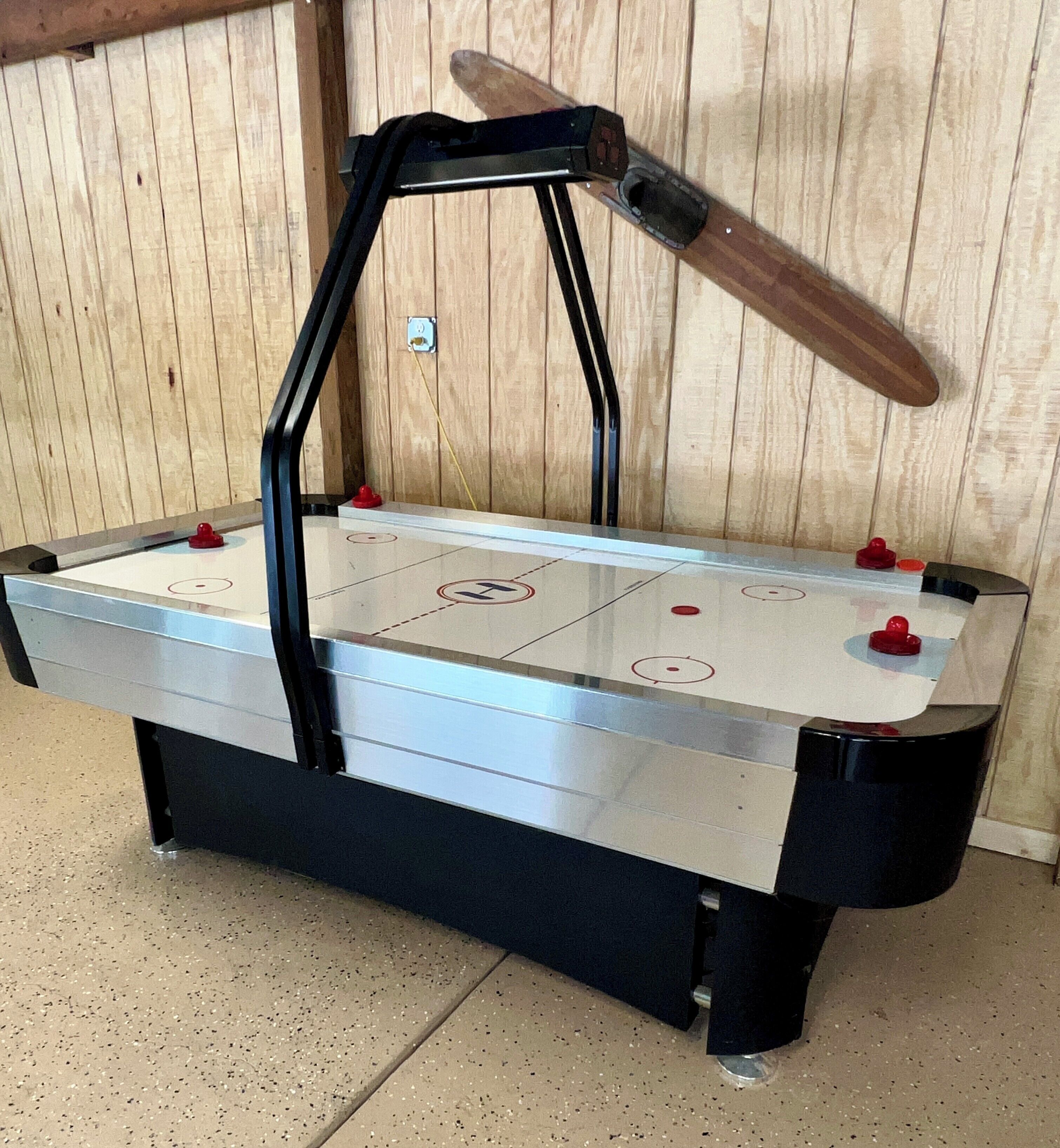 A pool table with a puck and a table tennis paddle.