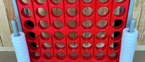 A red plastic board with multiple circular cutouts, supported by two blue cylindrical stands.