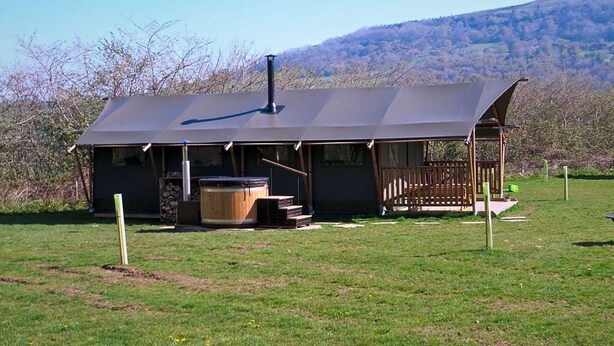 A rustic cabin with a metal roof, a hot tub, and a wooden deck.