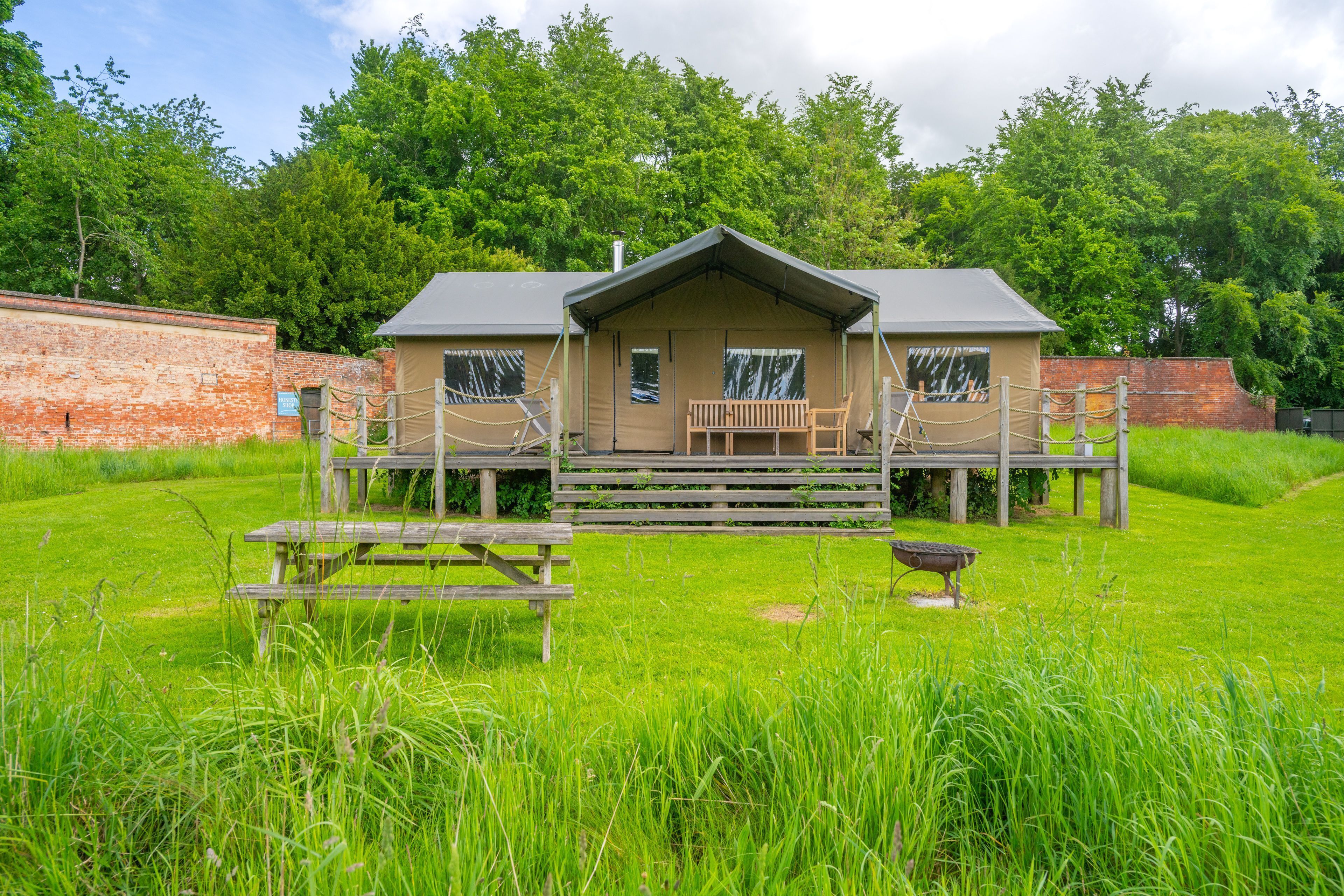 Un rustico chalet con veranda, una panca di legno e un tavolo da picnic in un'area erbosa.