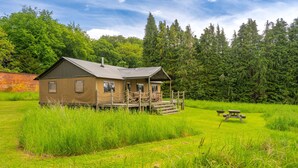 En hyggelig hytte med veranda og et picnicbord i en græsplæne.