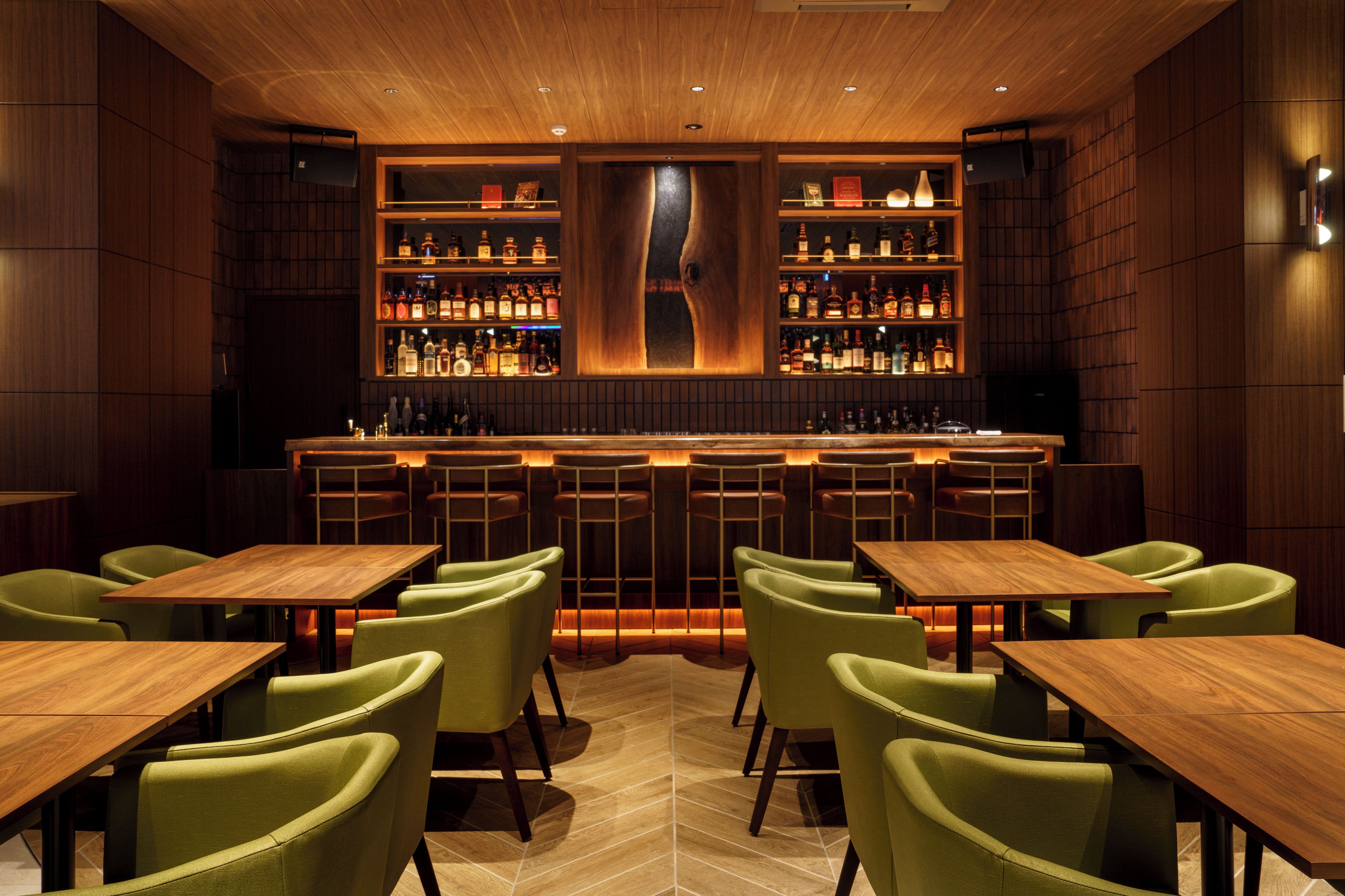A bar area with wooden furniture and shelves of bottles.