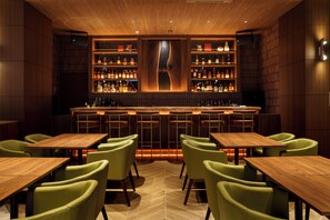 Zona de bar con muebles de madera y estantes llenos de botellas.