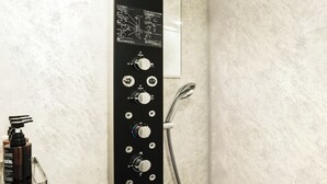 A modern bathroom with a vertical control panel, a handheld showerhead, and a built-in ventilation system. - BOUNCEE by RIHGA Fukuoka Hakata (Fukuoka)