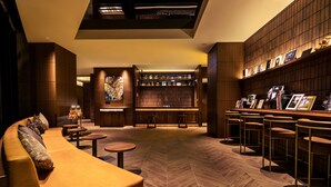A modern lounge area with a sofa, round tables, a bar with stools, and a bookshelf. - BOUNCEE by RIHGA Fukuoka Hakata (Fukuoka)