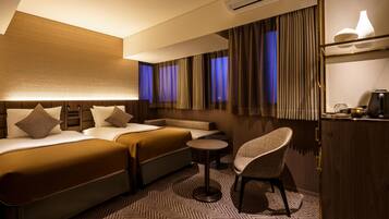 A hotel room with a bed, a sofa, a chair, an air conditioning unit, and a small table.