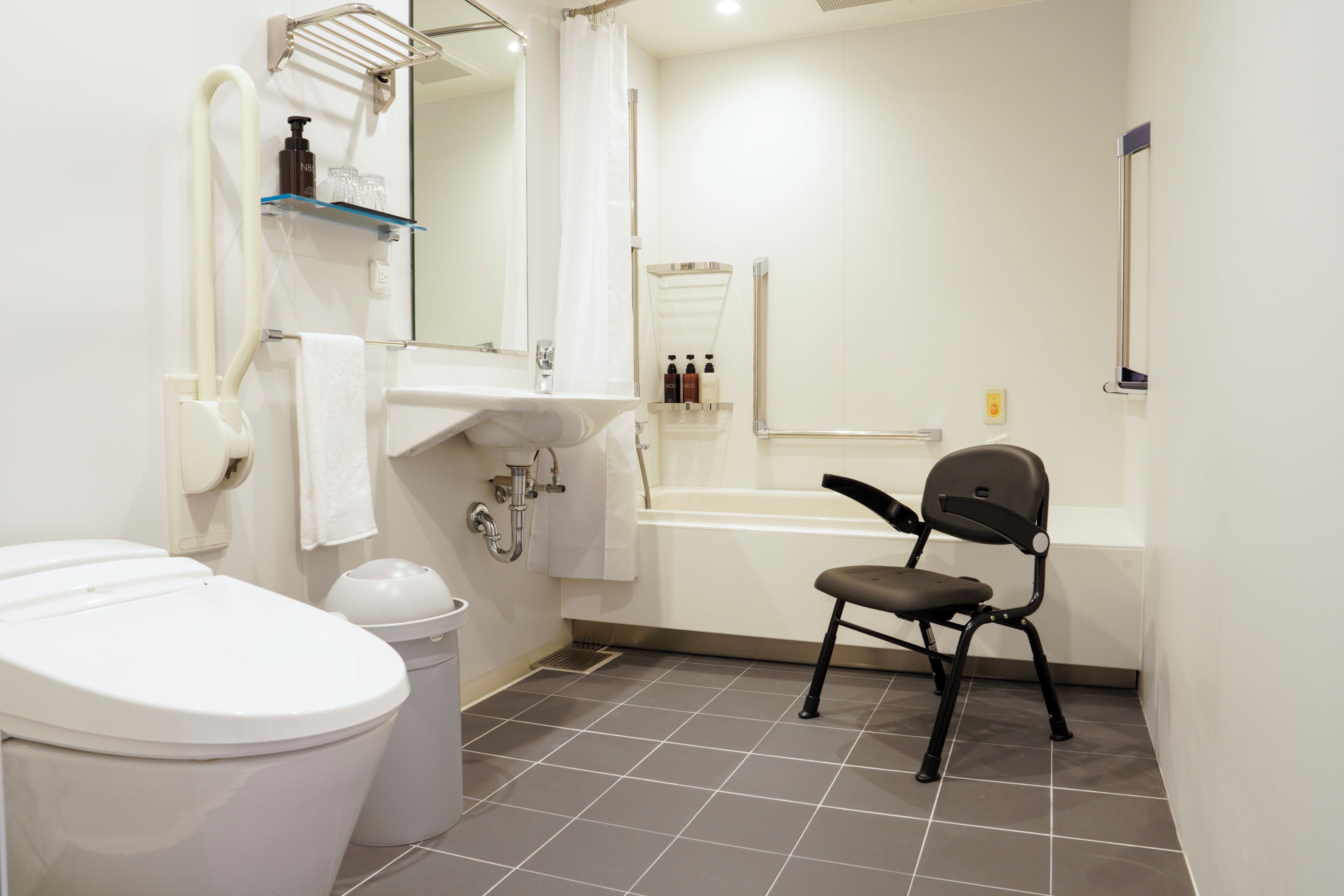 A modern bathroom with a toilet, sink, mirror, and shower area.