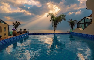 Una piscina con vistas al mar, rodeada de palmeras y un edificio de diseño moderno.