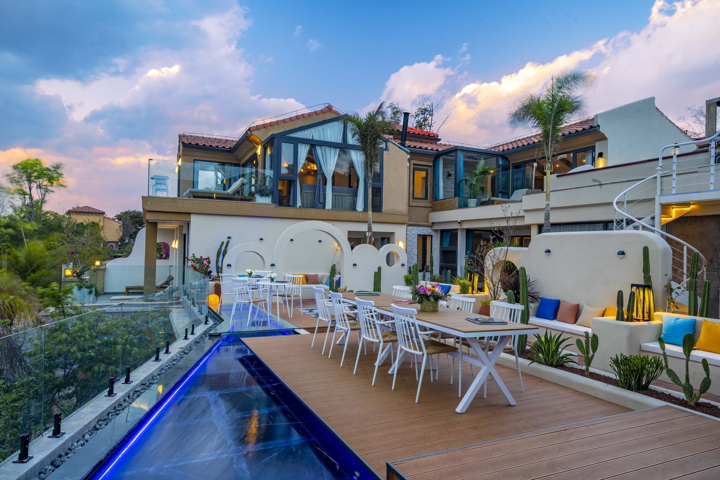 Una casa moderna con piscina, mobiliario exterior y una escalera.