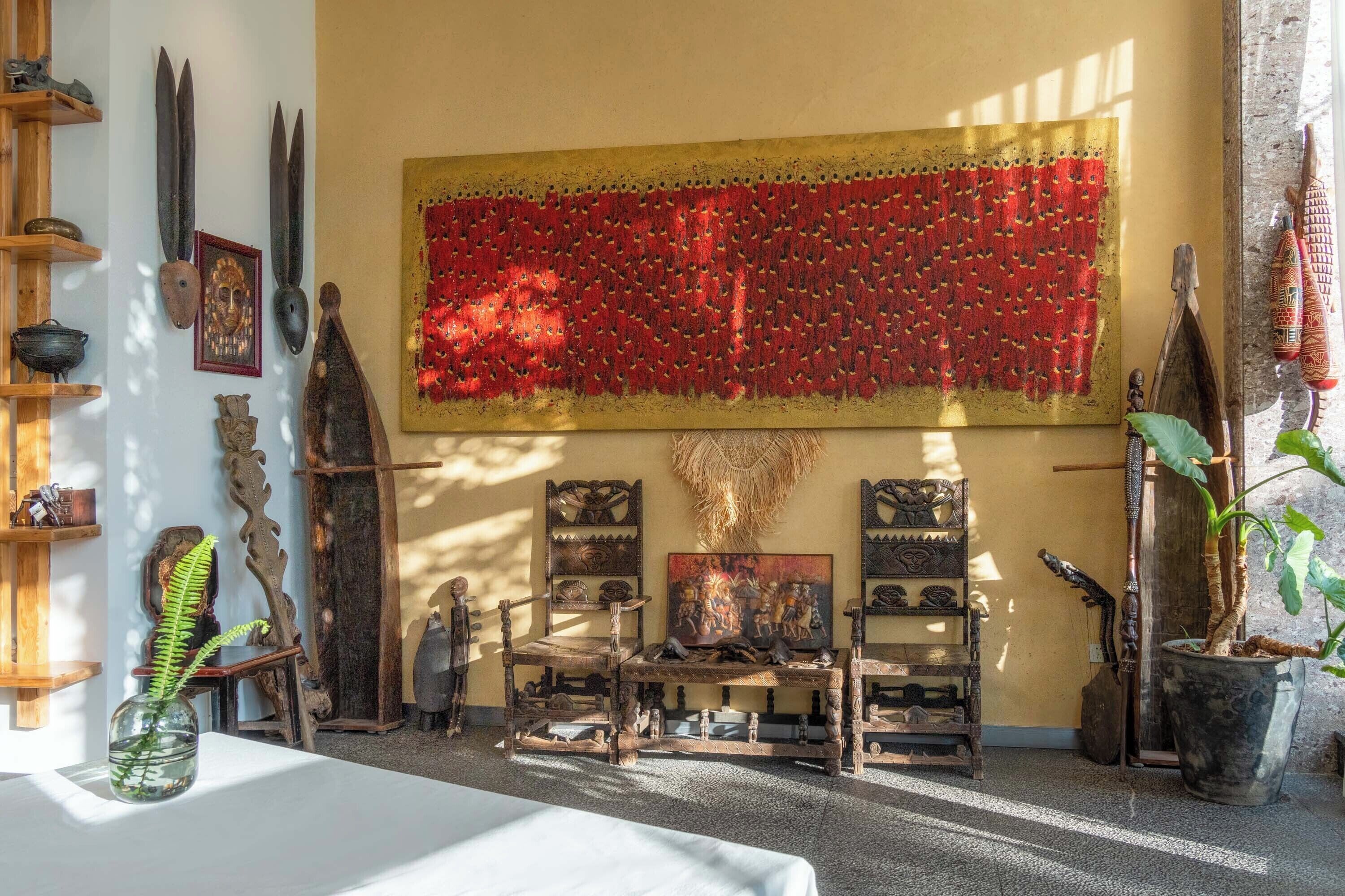 A room with a large red tapestry, wooden furniture, and various decorative items.