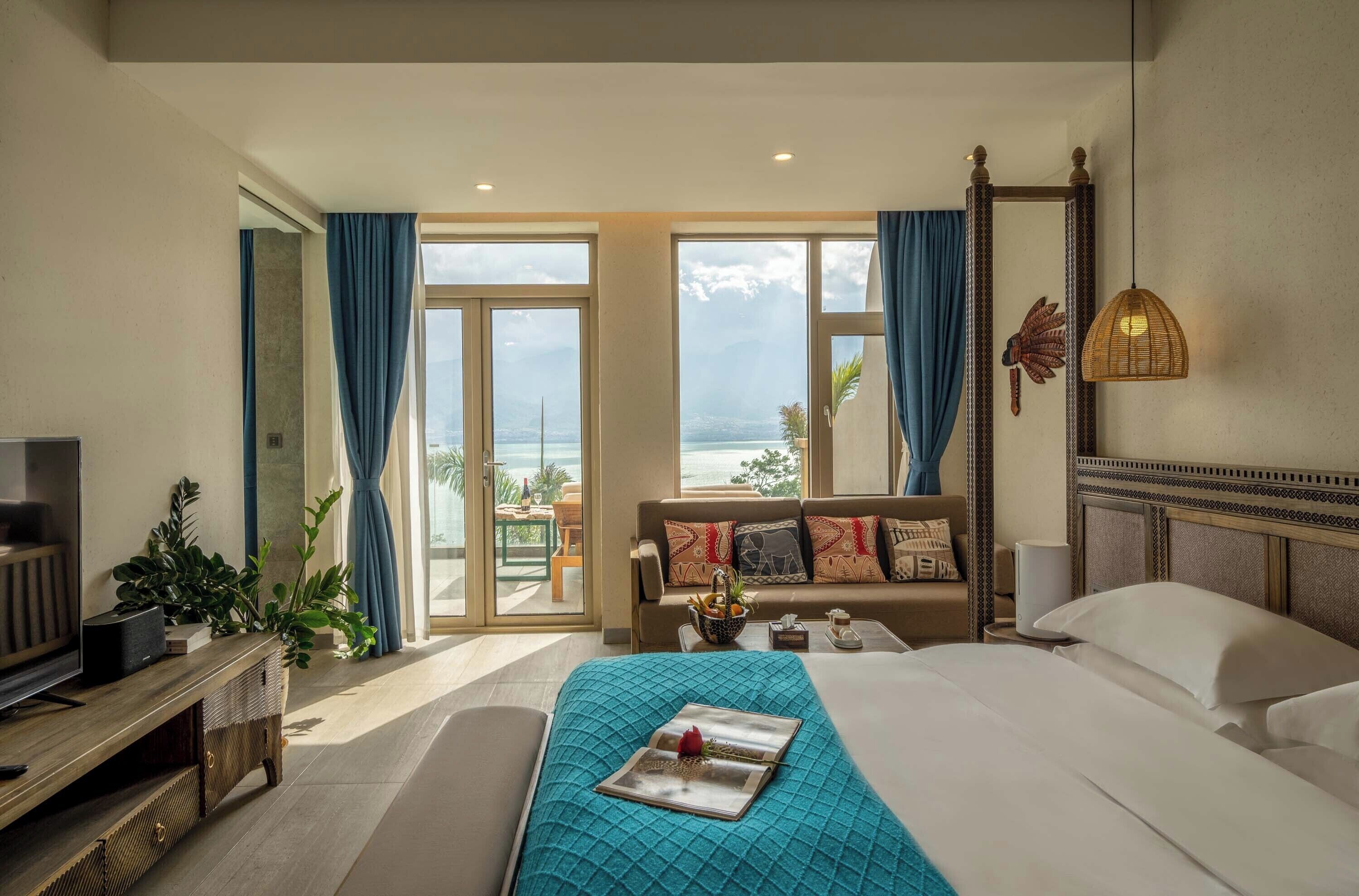 Ett hotellrum med en säng, en tv, en soffa och utsikt över havet.