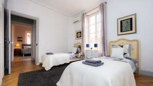 Een slaapkamer met twee bedden, een donker vloerkleed en een raam met gordijnen.
