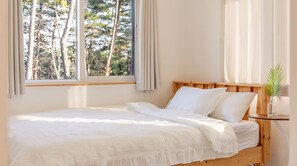 A single bed with a wooden headboard, white bedding, and a window with curtains. - Gangneung Eondeokwie Pension (Gangneung)