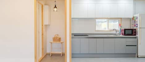 A modern kitchen with white cabinets, a microwave, and a window.