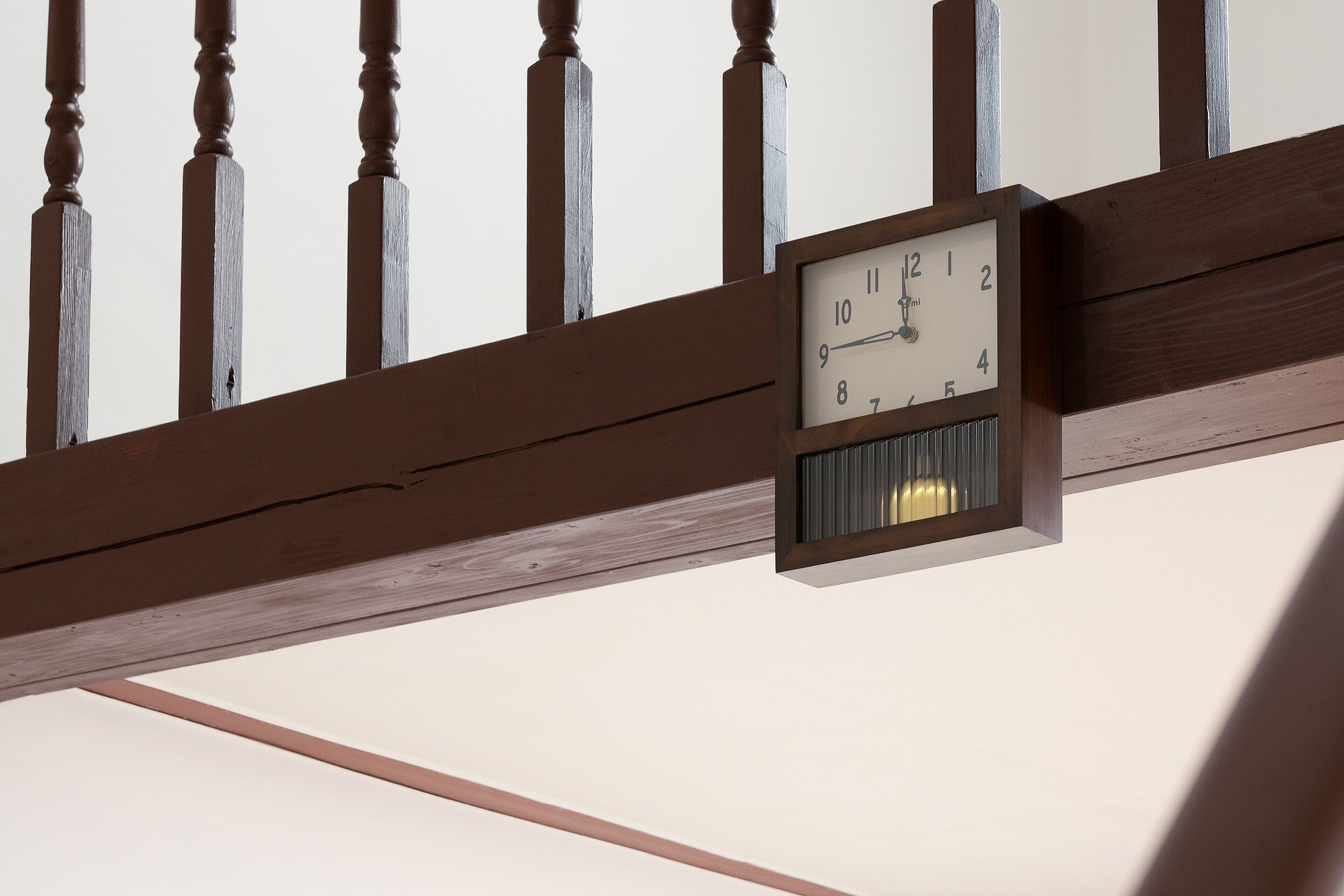 A clock mounted on a wooden beam with a white face and black numbers.
