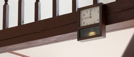 A clock mounted on a wooden beam with a white face and black numbers.