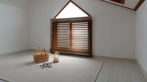A room with a sloped ceiling, a window with wooden blinds, a wicker basket, a glass lantern, and a magazine on the floor. - Ganghwa Aboha Pet-friendly Pension (Incheon)