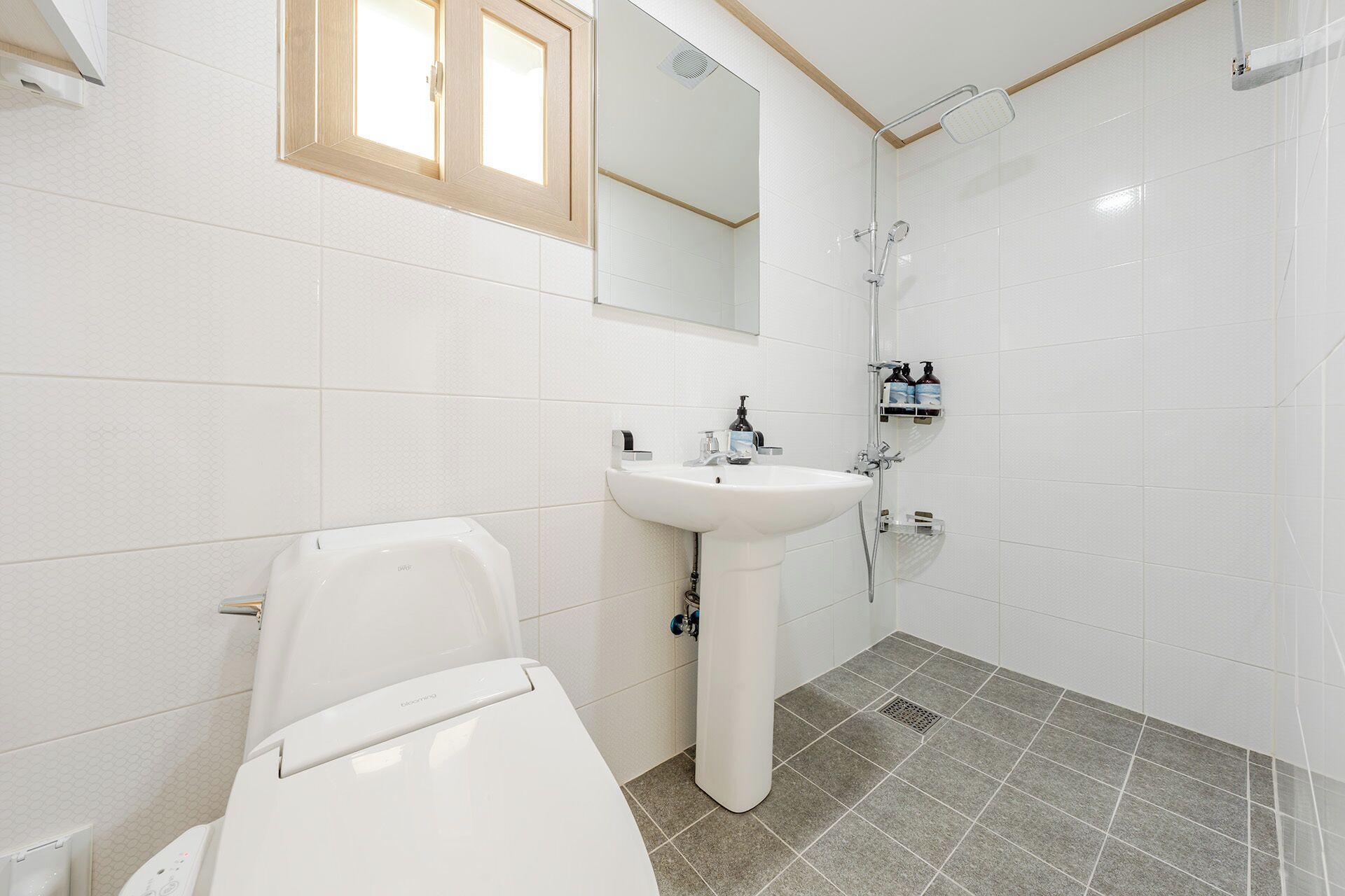 A bathroom with a toilet, sink, and shower.
