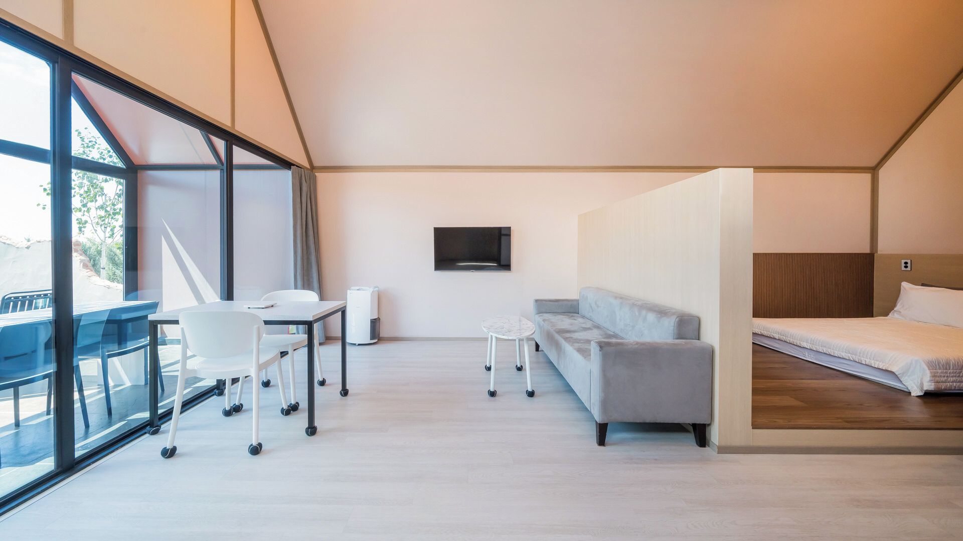 Et moderne hotelværelse med et stort vindue, en sofa, en seng, et lille bord og en stol.