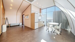 Eine moderne Küche mit Kühlschrank, Herd und Spüle, ein Essbereich mit Tisch und Stühlen sowie ein großes Fenster mit Blick.