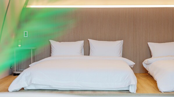 A hotel room with a large bed, two pillows, a headboard with vertical lines, and a green light on the wall. - Ganghwa Aiem Glamping (Incheon)