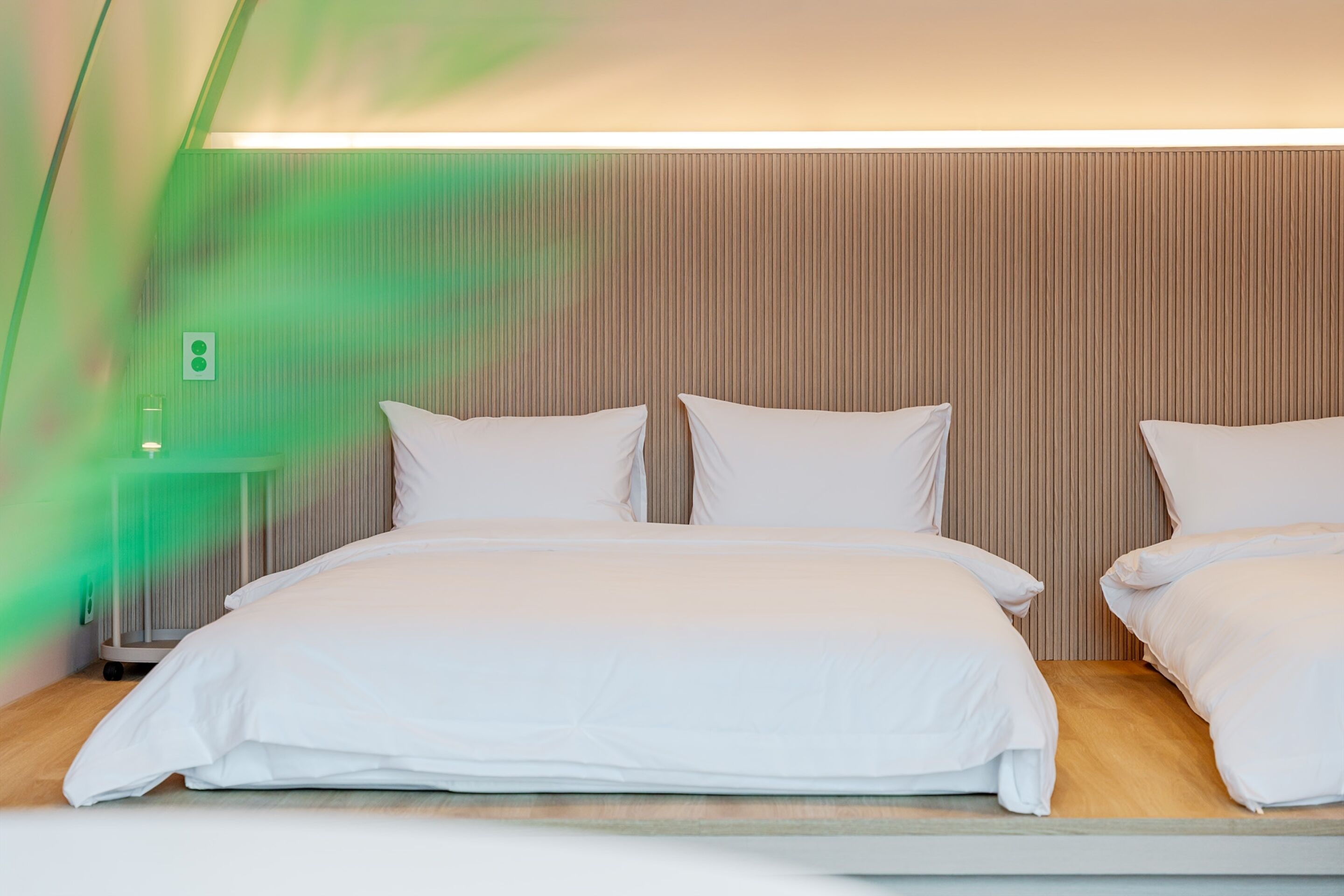 A hotel room with a large bed, a bedside table, and a wall-mounted light.