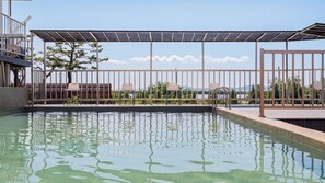 En swimmingpool med ett trädäck, stolar och en pergola med solpaneler.