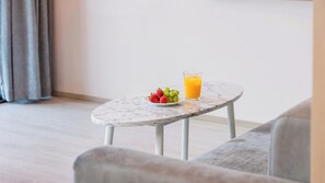 Ein kleiner runder Tisch mit Marmorplatte, einer Fruchtschale und einem Glas Orangensaft.