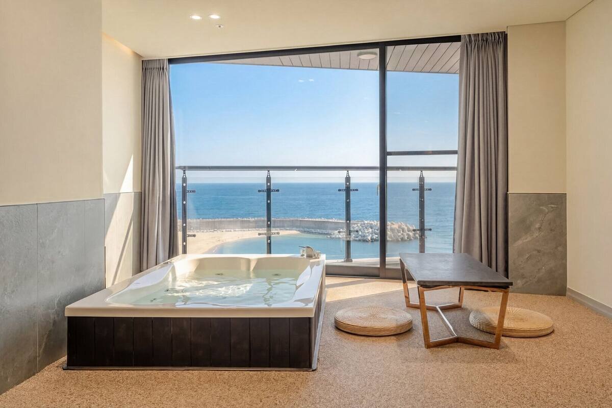 A balcony with a hot tub, a table, and a view of the sea.