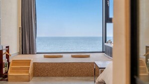 Una stanza con vista sul mare, una panca di legno, un tavolino e un termosifone.