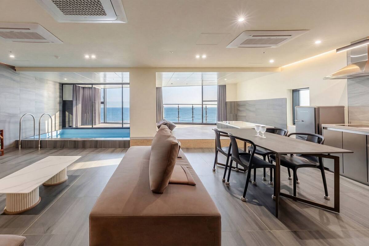 A modern hotel room with a pool, a dining area, and a kitchen.