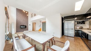 A modern kitchen with a built-in oven, a refrigerator, and a microwave. There is a dining area with a large table and chairs. - Gapyeong Meongstay Pension (Gapyeong)