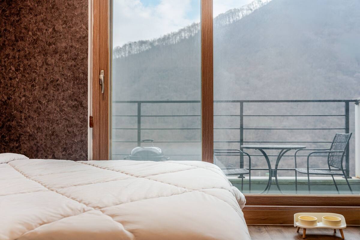 Ein Schlafzimmer mit einem großen Bett, einem Fenster und einem Balkon mit Tisch und Stühlen.