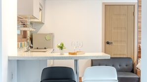 A modern kitchen with a countertop, two bar stools, a small potted plant, and a door. - Gapyeong Meongstay Pension (Gapyeong)
