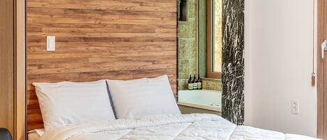 Una cama bien hecha con ropa blanca en una habitación con paneles de madera y un revestimiento de baldosas de mármol.
