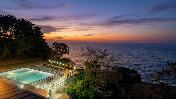 Ein Poolbereich mit Blick auf das Meer bei Sonnenuntergang.