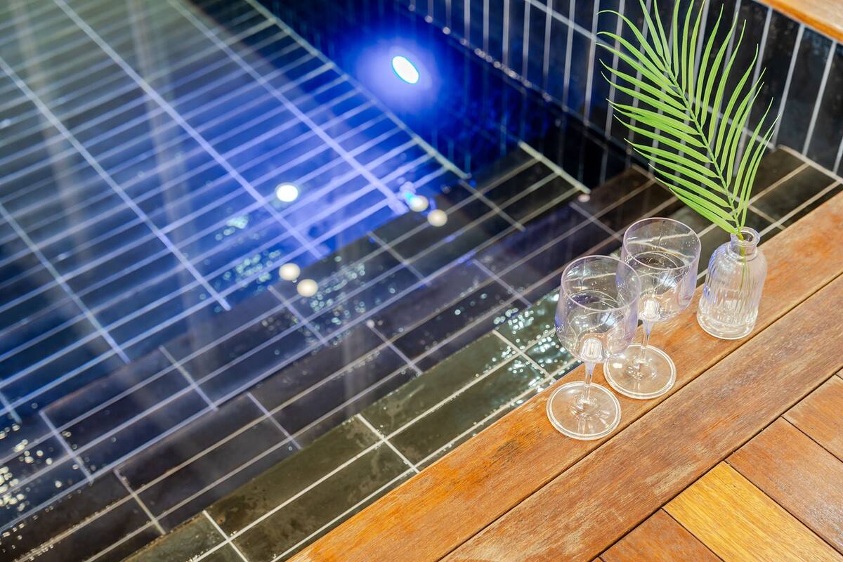 A wooden floor with a glass-topped table holding four glasses and a vase with a plant.