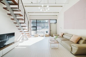 A modern living room with a flat-screen TV, a sofa, a coffee table, and a staircase. - Sokcho Night Sky Pension (Sokcho)