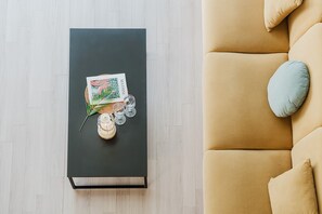 Egy modern nappali, melyben egy fekete dohányzóasztal, egy bézs színű kanapé világoskék párnával, és az asztalon egy kép látható.