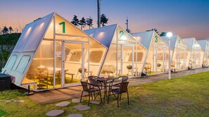 A row of numbered tents with glass doors, outdoor seating, and a grassy area. - Sokcho Night Sky Pension (Sokcho)