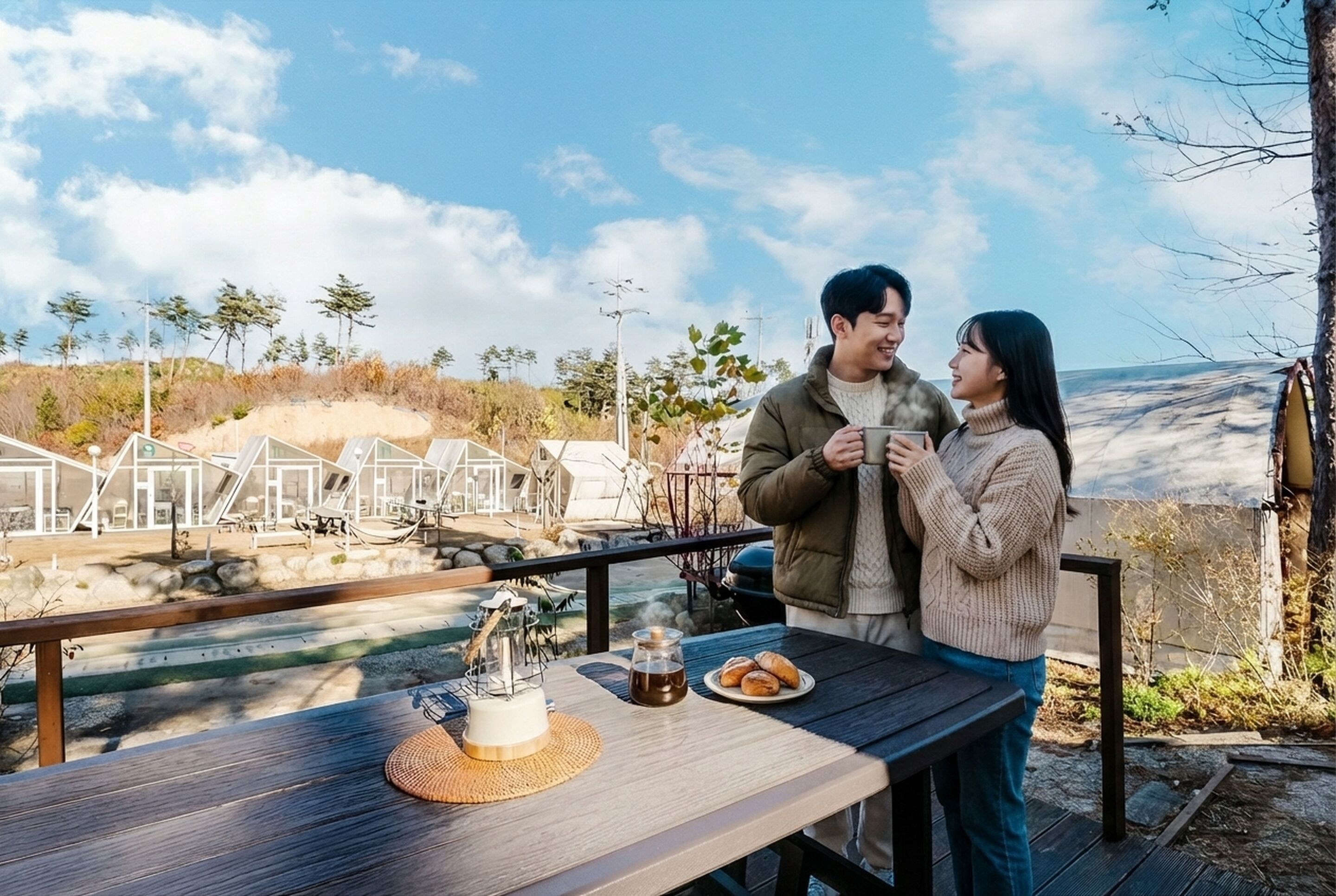 A couple sitting at a wooden table with a view of a modern building and trees in the background.