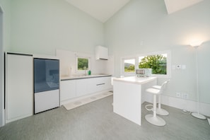 Cocina moderna con armarios blancos, microondas integrado y ventana con vistas a vegetación.