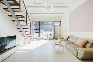 Una sala de estar moderna con un televisor de pantalla plana, un sofá, una mesa de centro y una escalera.