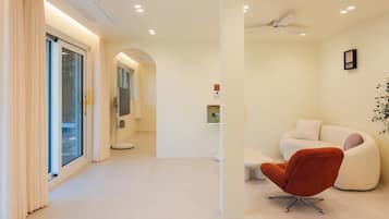 A modern interior with a white sofa, a red chair, and a ceiling fan.